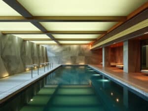 A modern circular sauna with wooden benches lining the walls, a central metal stove filled with rocks, and a gong hanging on the right. Natural light enters from a round ceiling window.