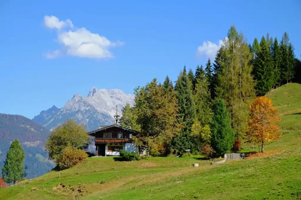 Contemporary alpine chalet with broad windows overlooking snow-capped mountains and pastoral valleys