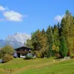 Contemporary alpine chalet with broad windows overlooking snow-capped mountains and pastoral valleys