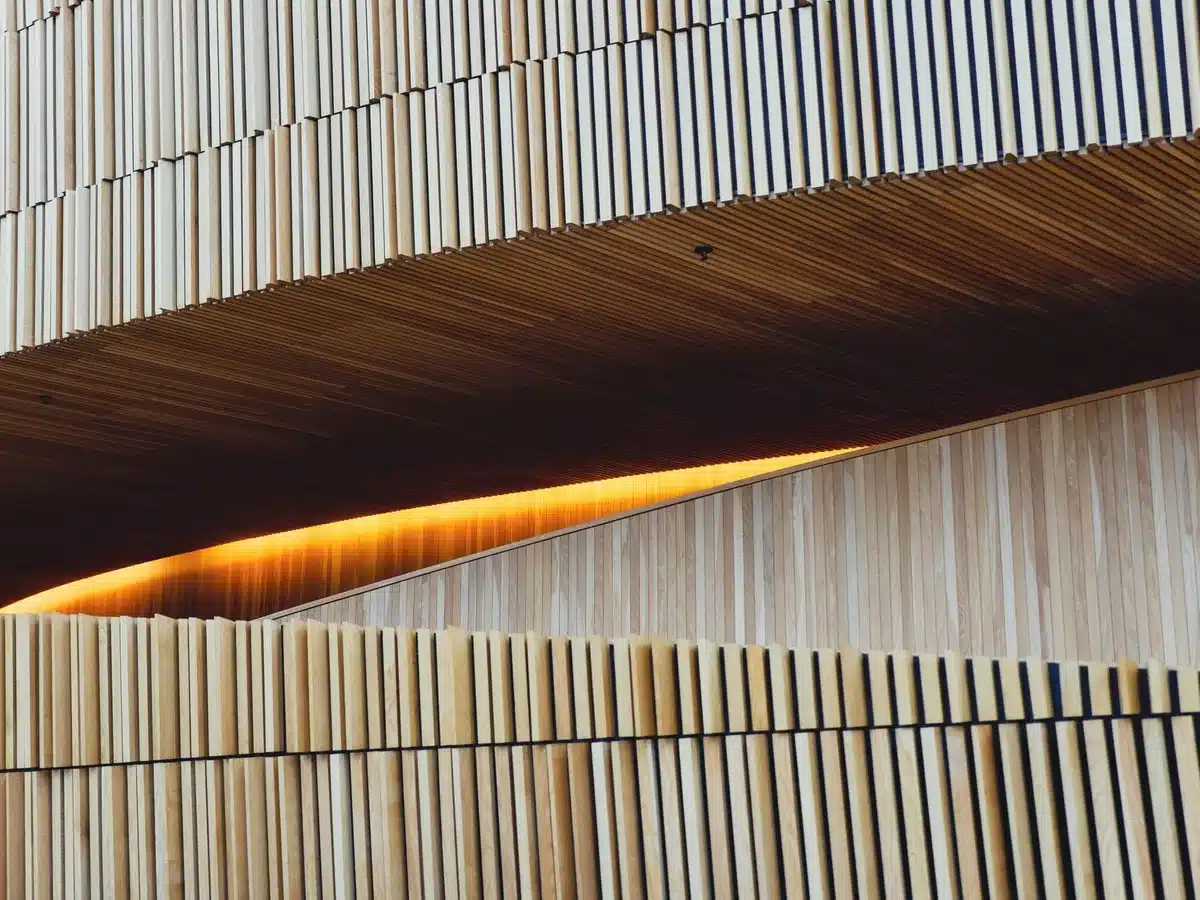 Sculpted wooden wall with tiered layers in warm ochre and umber tones, integrating seating and product display in a mode